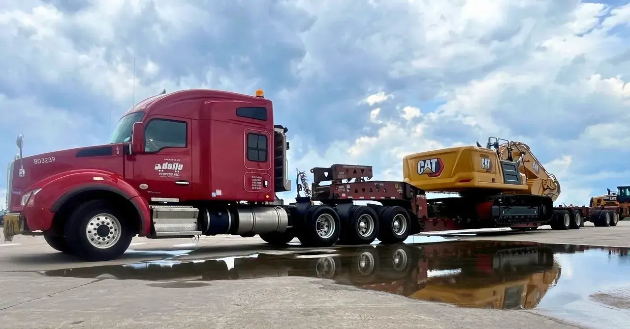 Daily driver moves Caterpillar equipment on open deck trailer